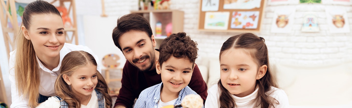 Eine junge Frau und ein junger Mann spielen mit drei vergnügten Kindern