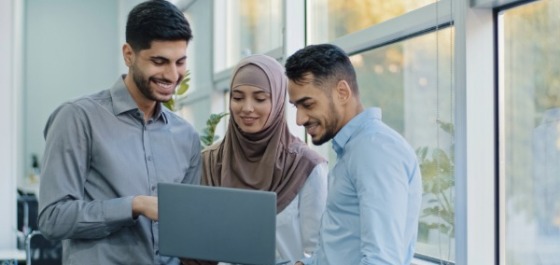 2 männliche und eine weibliche Fachkraft aus dem Ausland diskutieren am Notebook