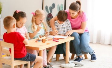 Eine junge Frau mit vielen Kindern in einem Kindergarten