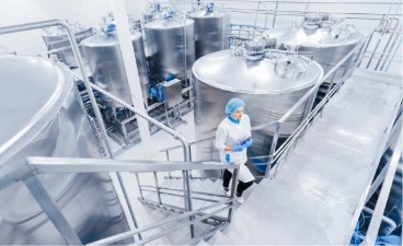 Eine Person mit Arbeitskleidung geht eine Treppe hoch in einer Käserei