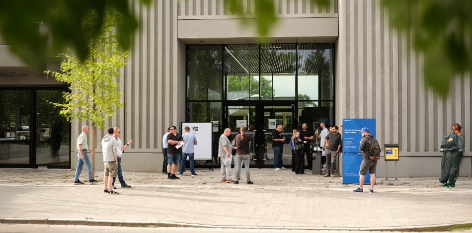 Eine Halle von außen mit Menschen davor