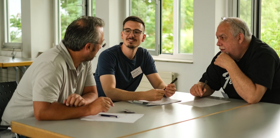 3 Männer diskutieren an einem Tisch