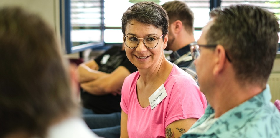 Eine Referentin spricht mit 2 Besuchern eines Fachforums