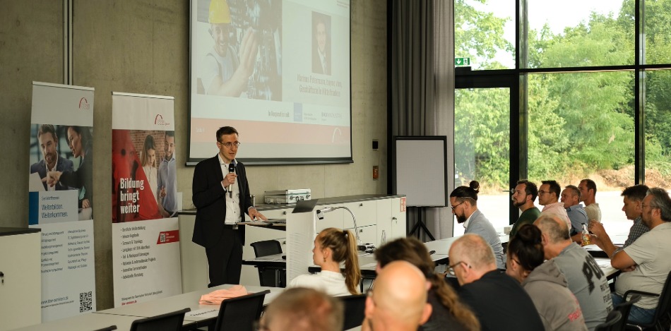 Viele Menschen in einer Aula hören einem Redner zu