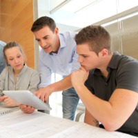 Ausbilder erklärt einer jungen Frau und einem jungen Mann ein Thema 