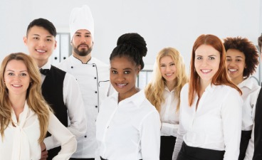 Junge Servicekräfte aus  Gastronomie aus vielen Ländern stehen zusammen und lachen