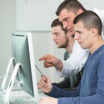 Ein Trainer schult 2 junge Männer am PC