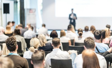 Mann spricht vor Publikum in einem Saal